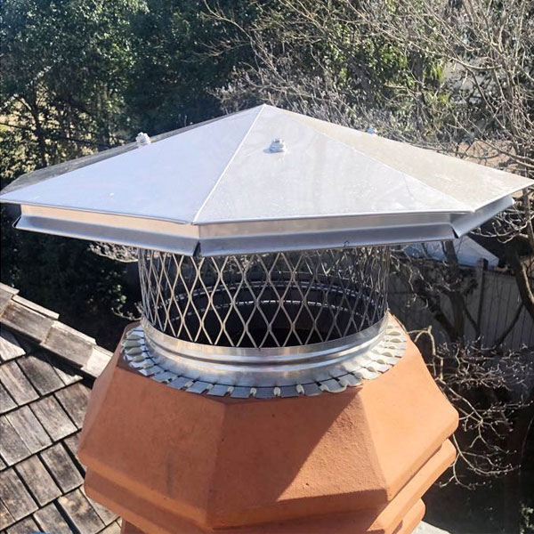 Original photo of custom stainless pot topper with octagonal lid-Owens Chimney Cover Stainless steel octagonal pot topper with trees in background